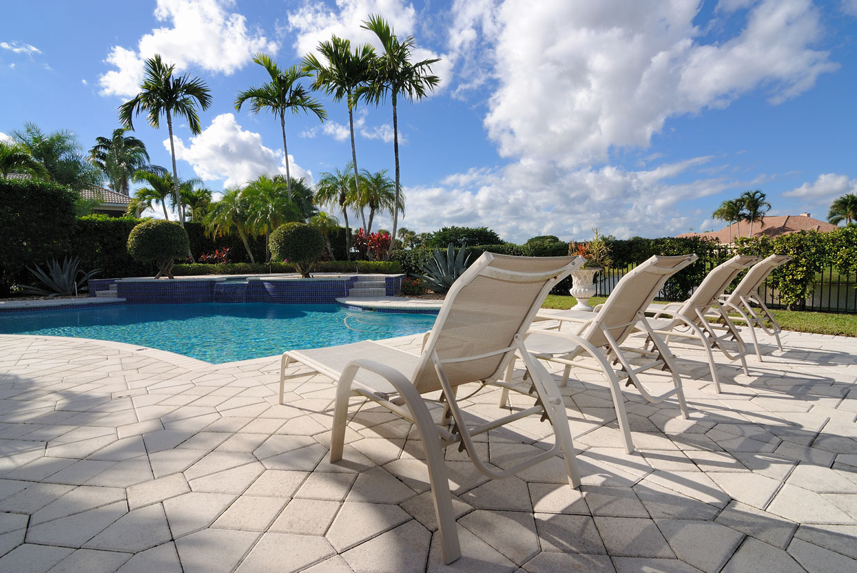Resort-style backyard pool with lounge chairs and custom patio by Emerald Isle Pools