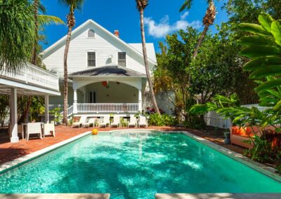 Custom residential swimming pool with tropical landscaping and classic home design by Emerald Isle Pools